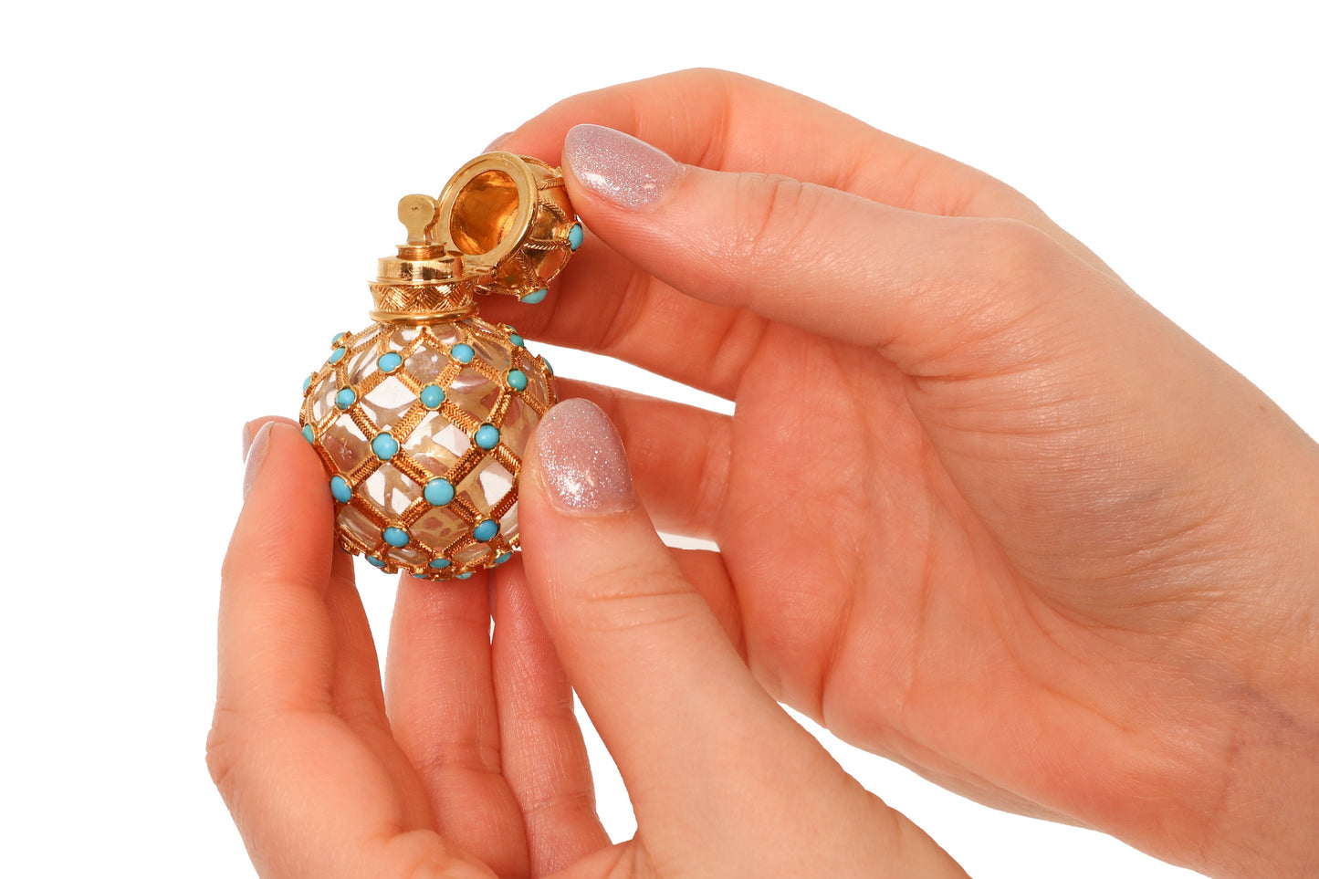A yellow gold decorative perfume bottle with cabochon turquoise, held in hands