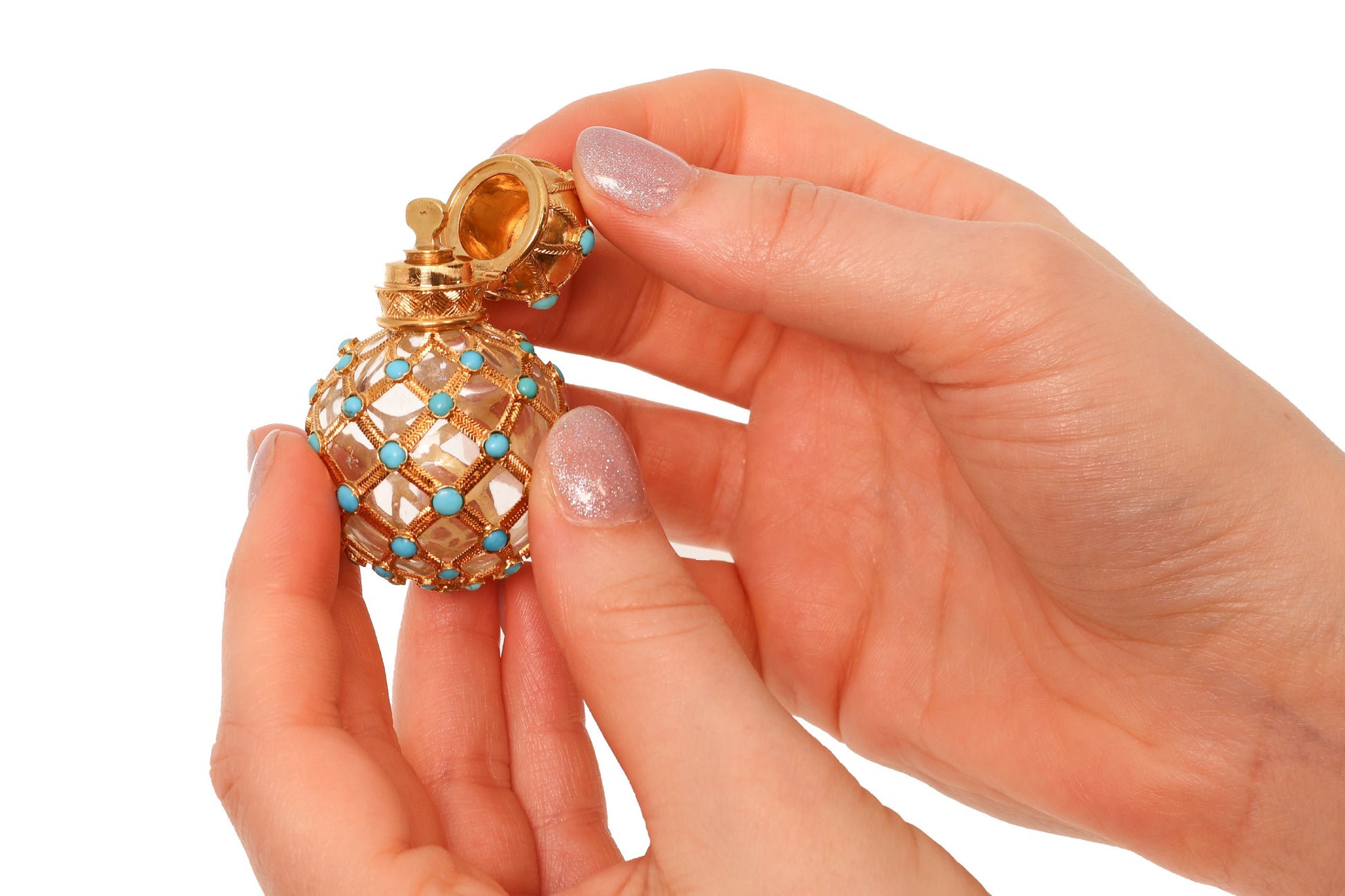 A yellow gold decorative perfume bottle with cabochon turquoise, held in hands