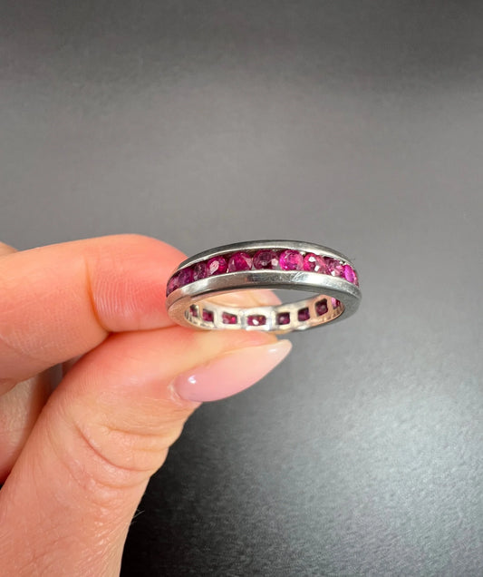 A ruby full eternity band in platinum, held in a hand