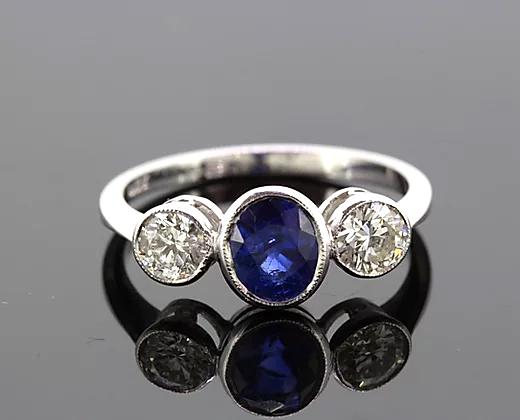 Oval Sapphire and Diamond Trilogy Ring; three-stone ring featuring 1.15ct oval-cut sapphire flanked by two diamonds totaling 0.67cts, 18ct white gold