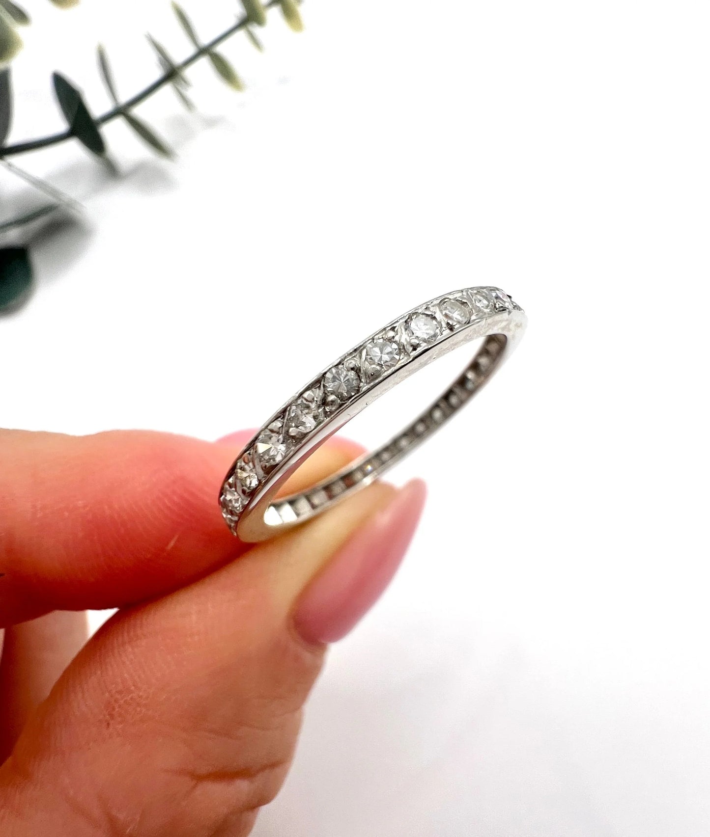 A platinum and diamond full eternity band ring, held in a hand