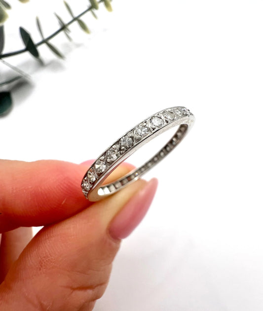 A platinum and diamond full eternity band ring, held in a hand