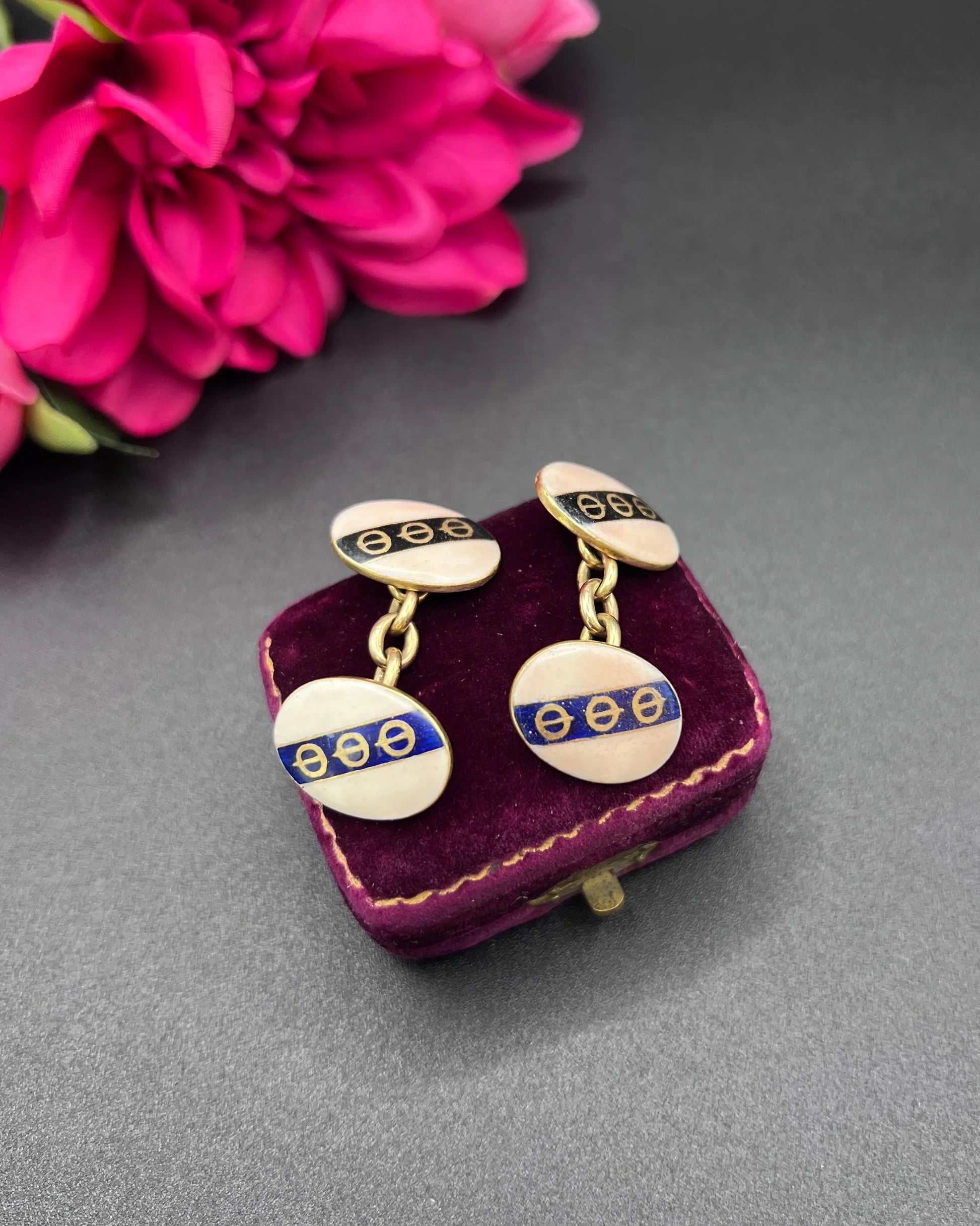 A pair of yellow gold enamel striped cufflinks with chain link fittings, on an antique box