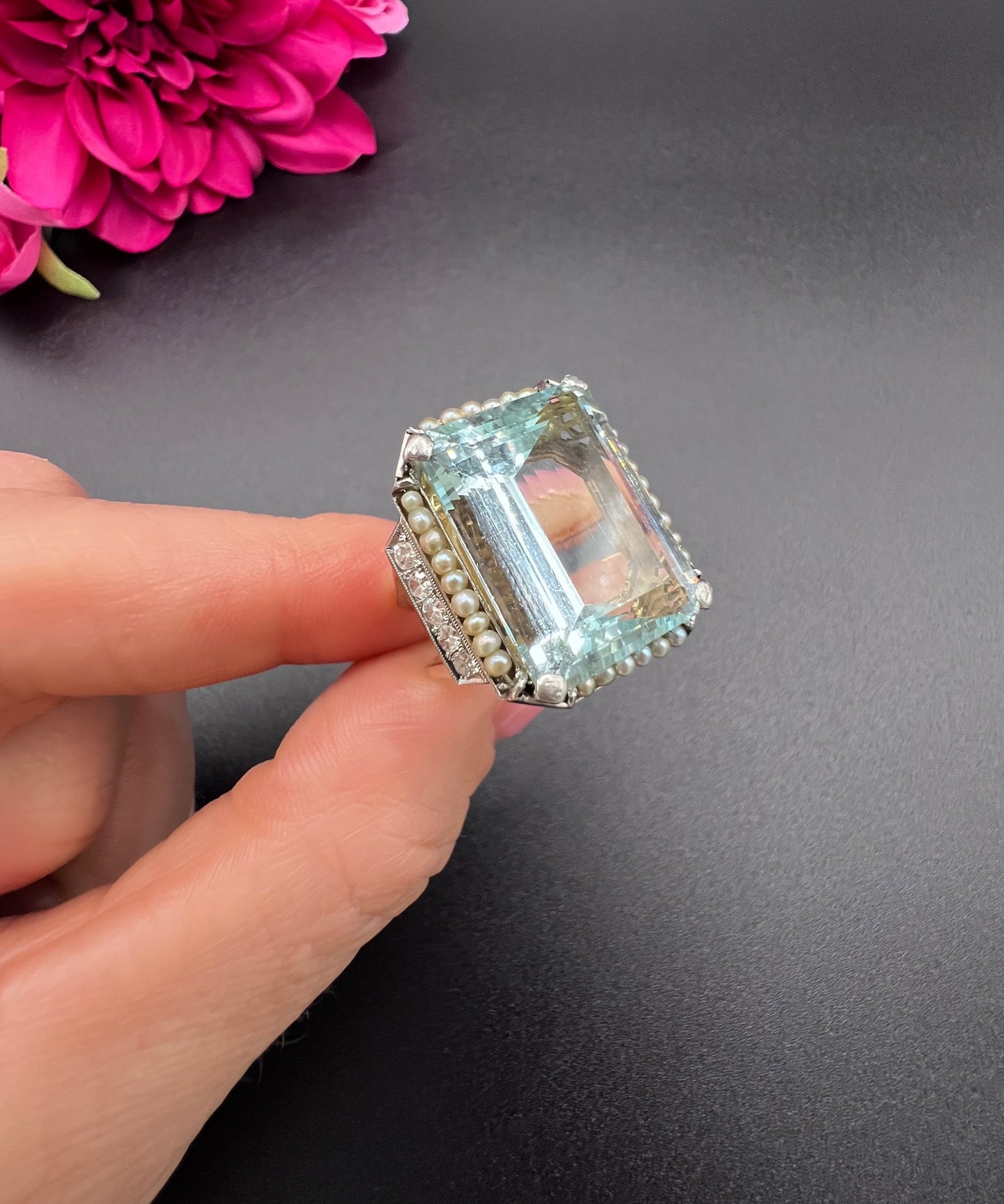 An aquamarine, pearl and diamond large cocktail ring in yellow gold and platinum, held in a hand