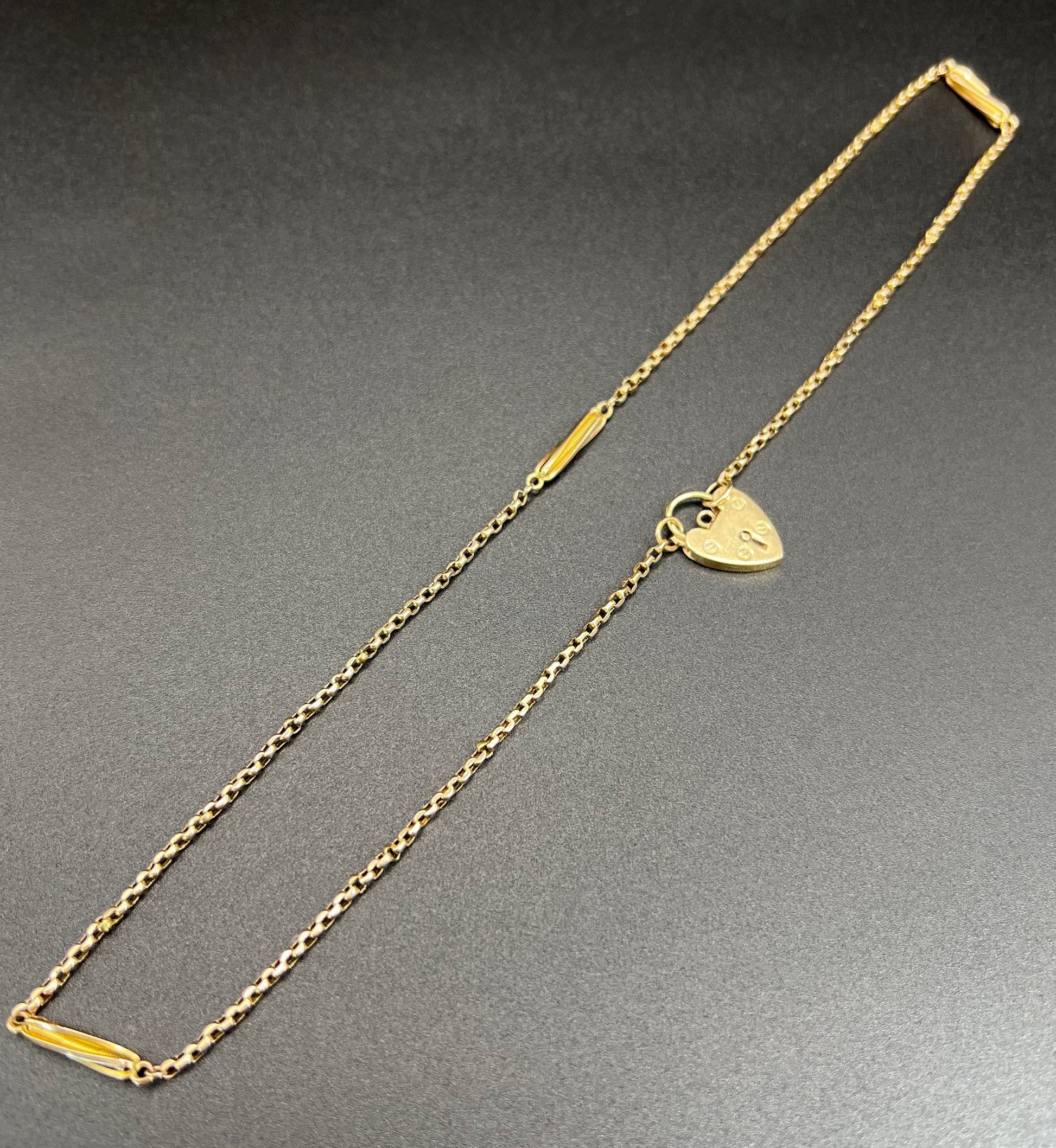A yellow gold fancy link chain with a heart padlock
