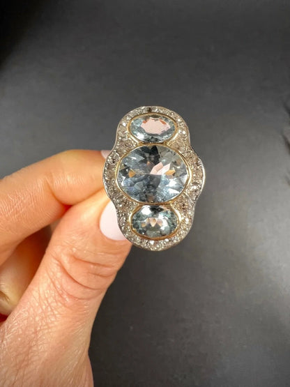 An aquamarine and diamond cocktail cluster ring, held in a hand