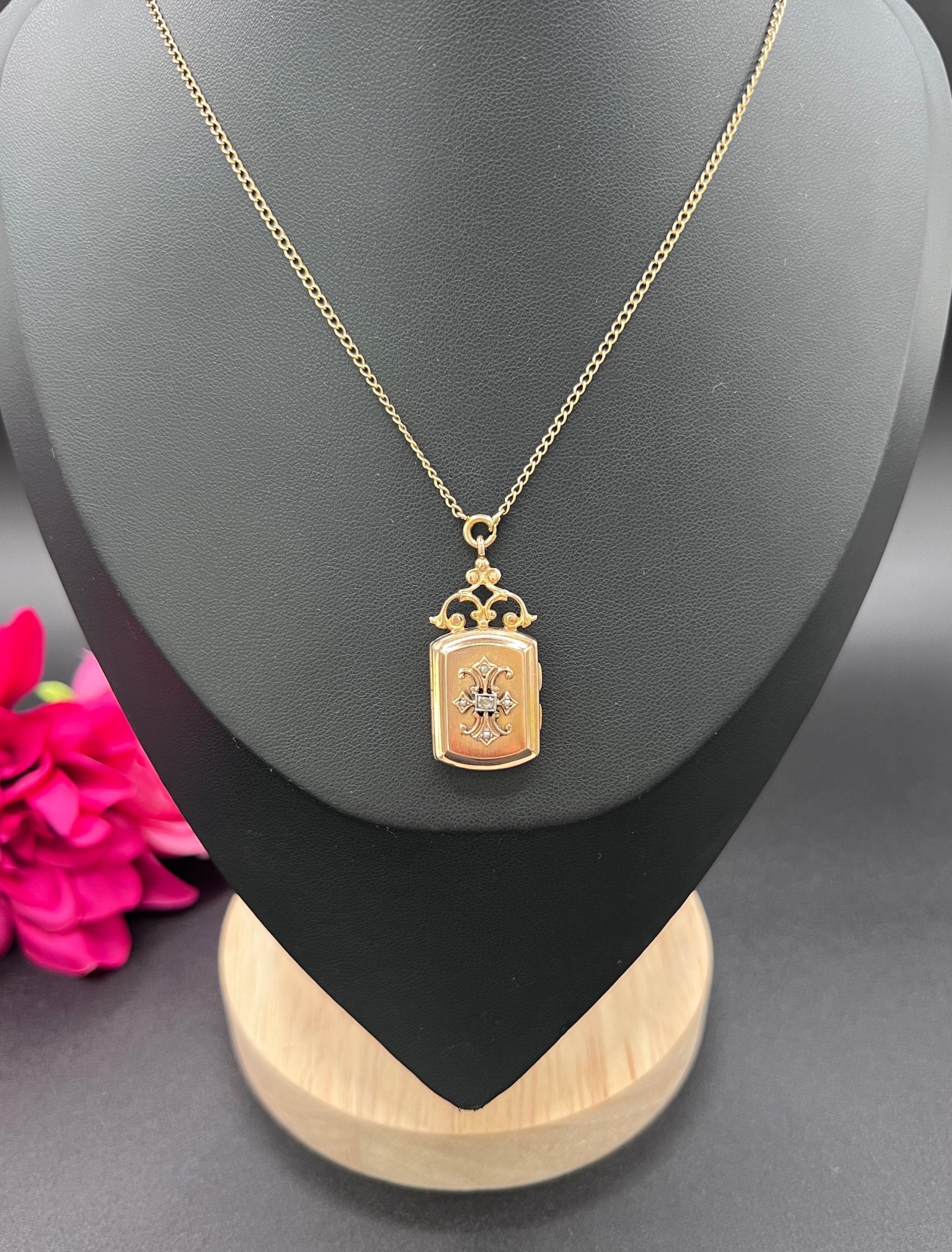 A yellow gold ornate locket with diamond fleur-de-lis detail, with a chain, modelled on a black jewellery bust
