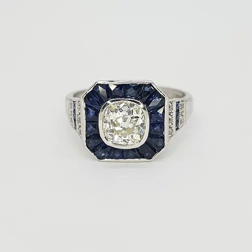 Diamond and Sapphire Calibre Cluster Target Ring; 1.20 carat diamond surrounded by calibre-cut sapphires, rows of diamonds and sapphires to the shoulders, in 18ct white gold