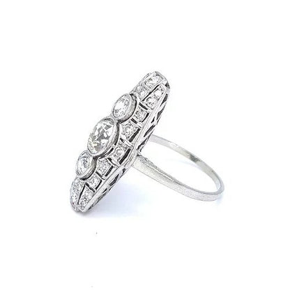 Art Deco Diamond and Platinum Three Stone Cluster Plaque Ring; featuring three brilliant cut diamonds in vertical formation surrounded by smaller circular diamonds, set in a pierced platinum mount with millegrain edging