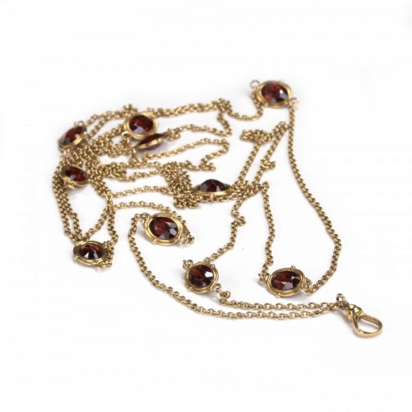 Antique Edwardian Garnet and Gold Long Chain Necklace; ten oval spectacle set garnets evenly spaced along a 148cm yellow gold trace chain, with swivel clasp, Circa 1910