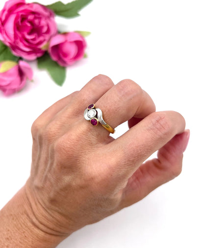 A three stone ruby and diamond crossover ring in platinum and yellow gold, modelled on a hand