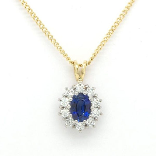 Sapphire and Diamond Oval Cluster Pendant; 0.50 carat oval faceted sapphire surrounded by 1.04 carats of round brilliant-cut diamonds in 18ct white gold. Hung from an 18ct yellow gold bale to an 18ct yellow gold 18-inch curb chain