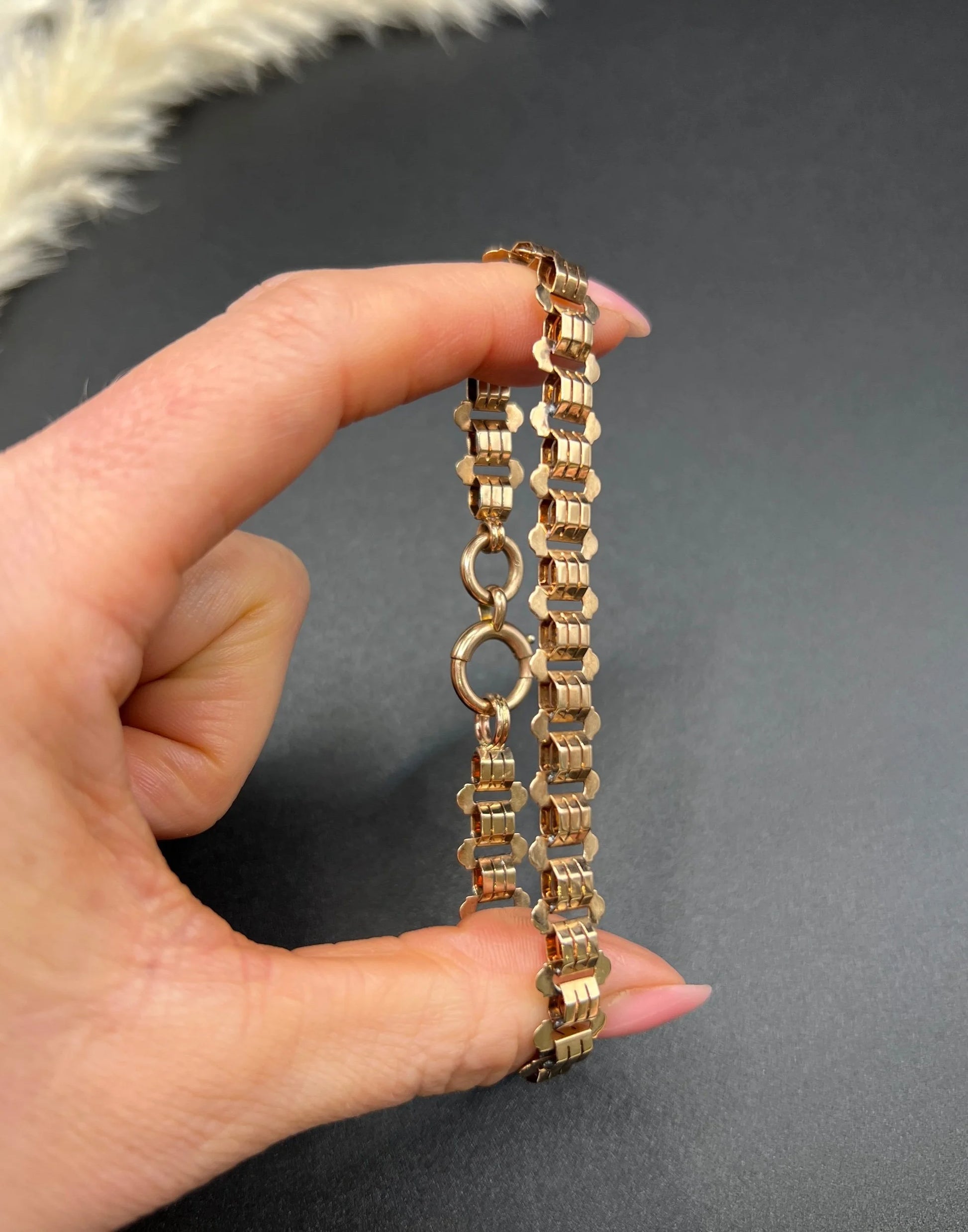 A rose gold fancy link bracelet, held in a hand