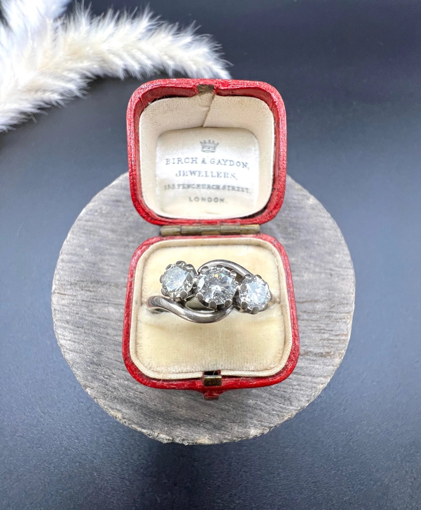 A three stone diamond crossover ring, in a red antique ring box