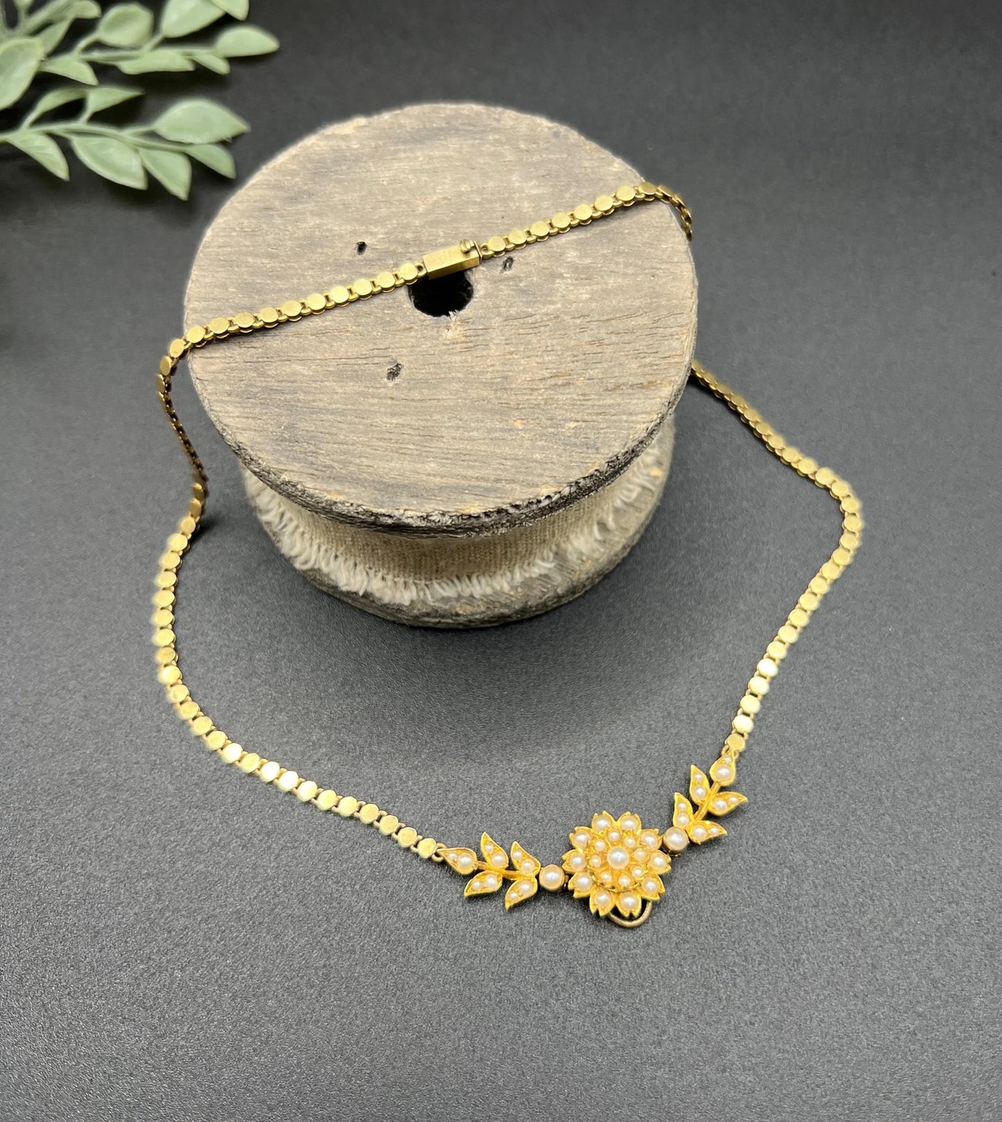 A yellow gold pearl floral necklace with integrated chain