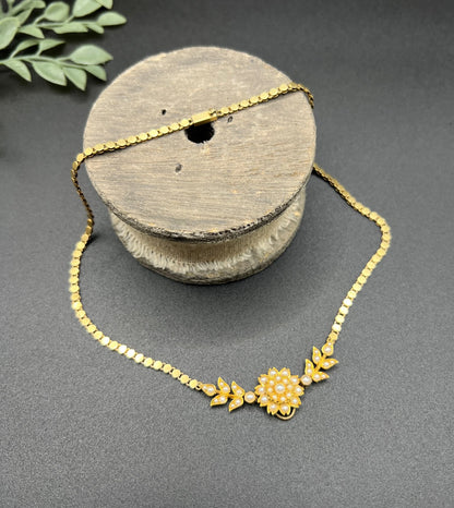 A yellow gold pearl floral necklace with integrated chain