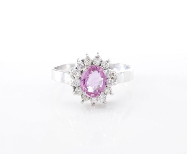 Vintage Pink Sapphire and Diamond Oval Cluster Ring; central 1.00ct oval pink sapphire surrounded by 0.39cts round brilliant-cut diamonds, in 18ct white gold. Circa 1970s