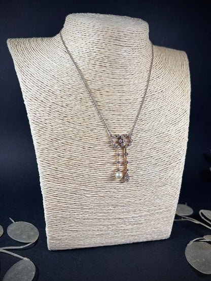 An antique diamond and pearl double drop pendant necklace, modelled on a light coloured jewellery bust