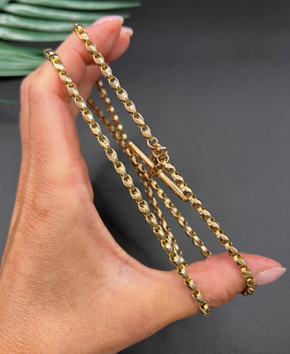 A rose gold tulip link chain necklace with a dog clip clasp and T-bar, held in a hand