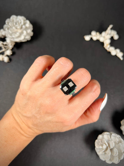 A geometric black onyx ring with diamonds and emeralds in white gold, modelled on a hand
