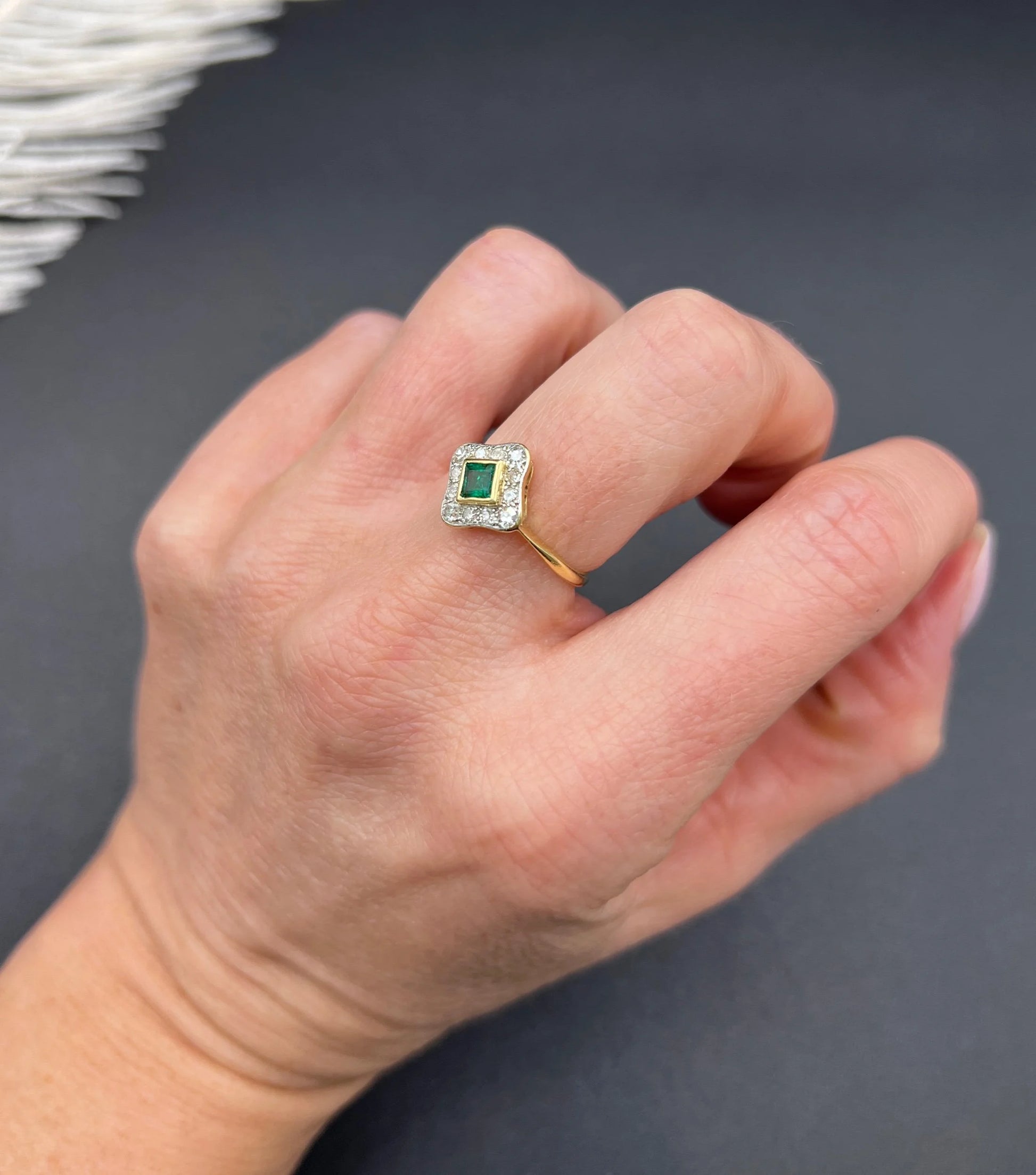 An emerald and diamond cluster ring in yellow gold and platinum, modelled on a hand