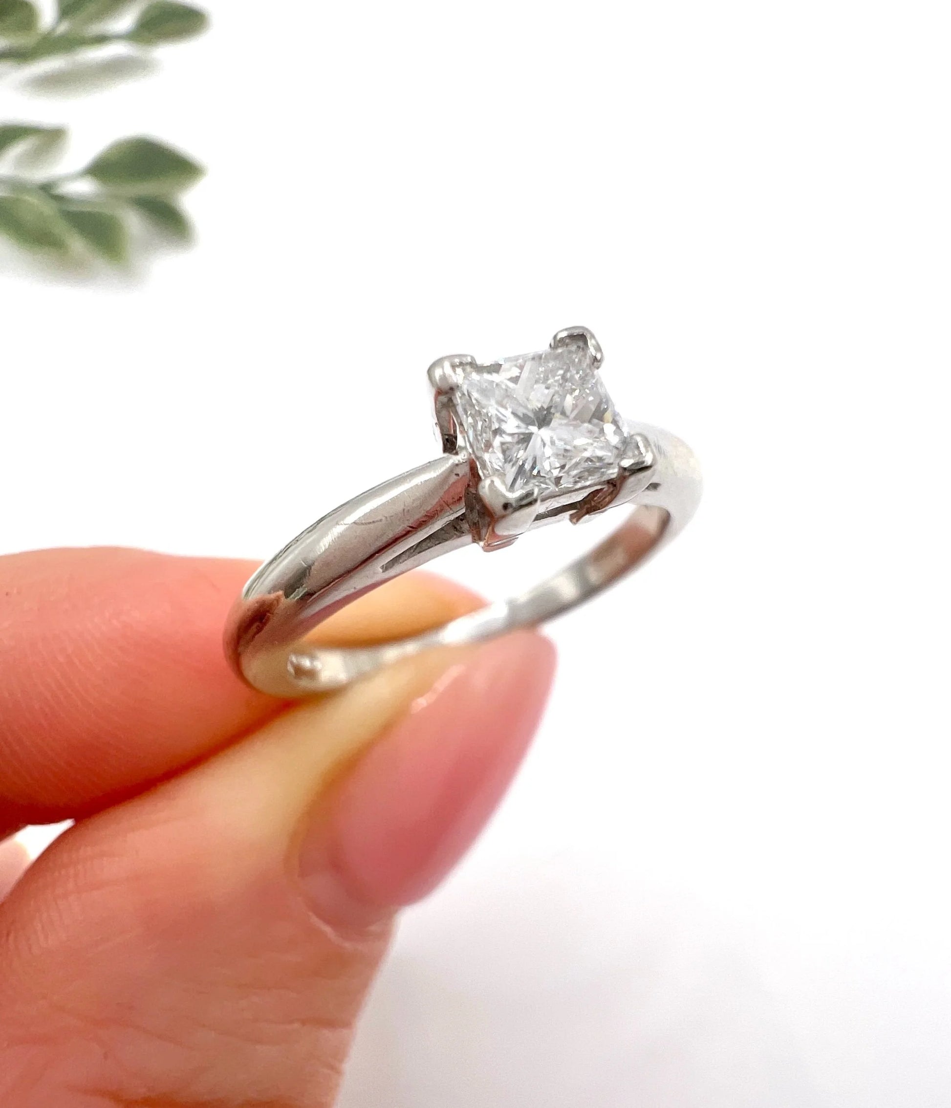 A princess cut diamond solitaire ring in platinum, held in a hand