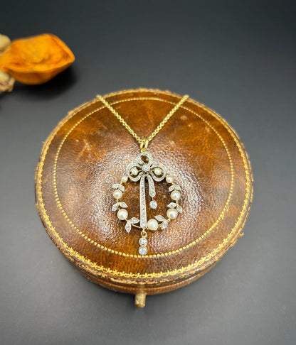 A pearl and diamond bow pendant in gold and platinum, with a chain