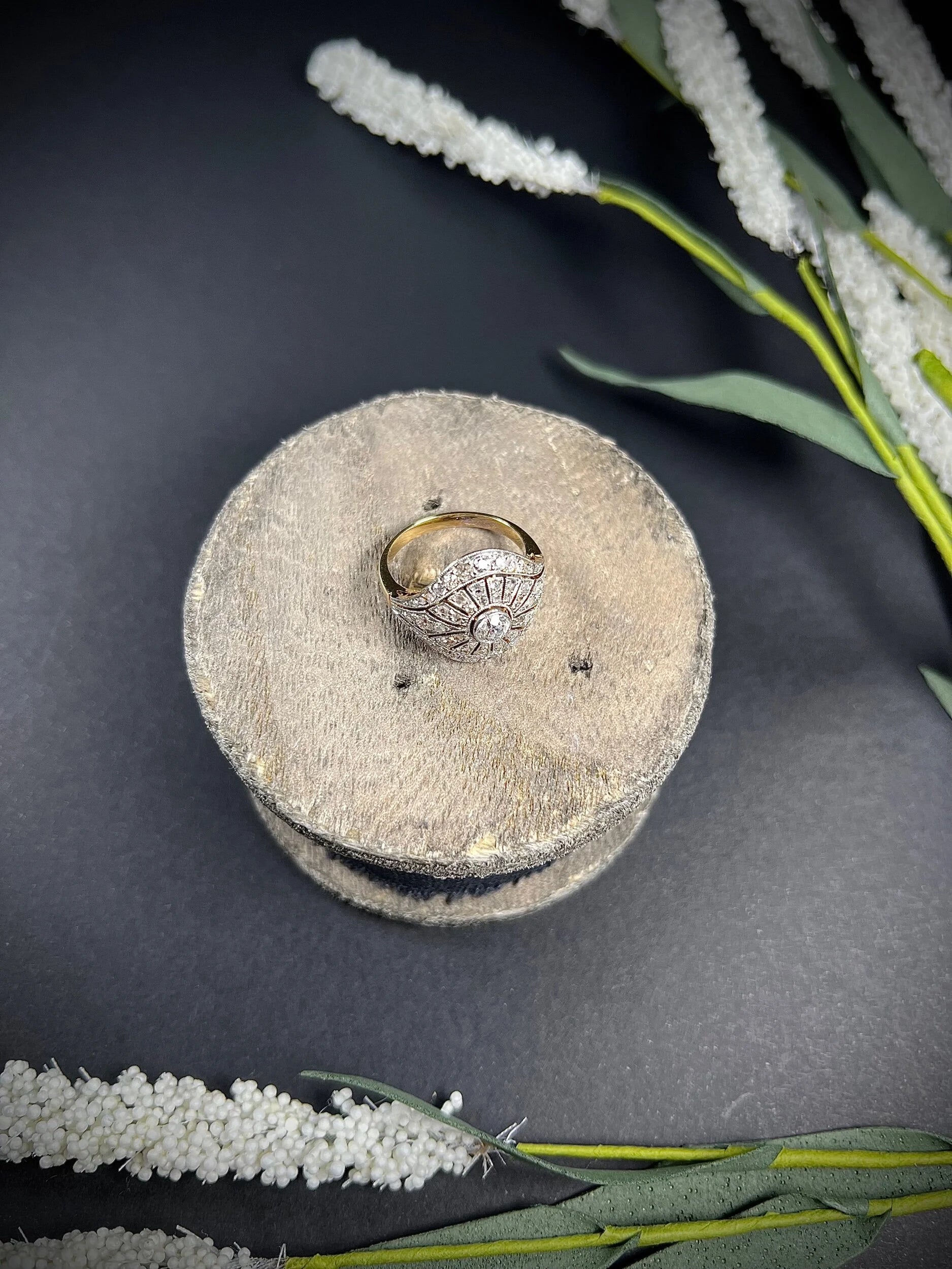 A diamond cocktail ring in yellow and white metal sat on top of a wooden object