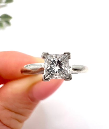 A princess cut diamond solitaire ring in platinum, held in a hand