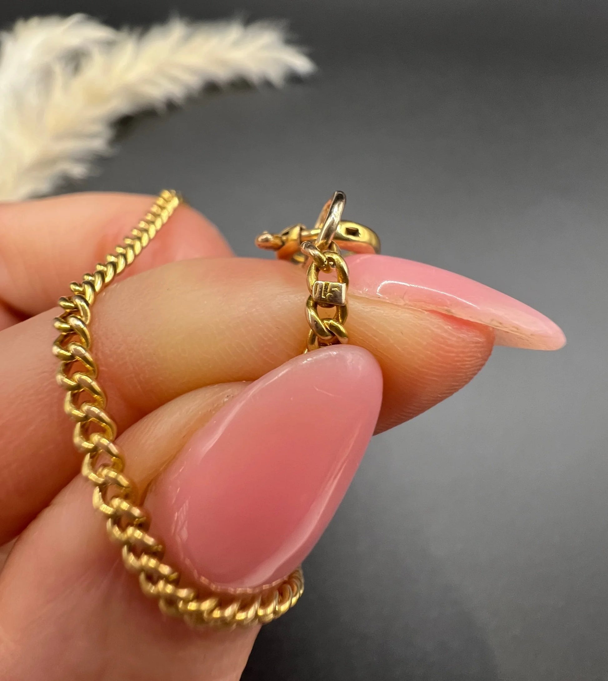 Close-up of a stamp on a yellow gold curb link chain