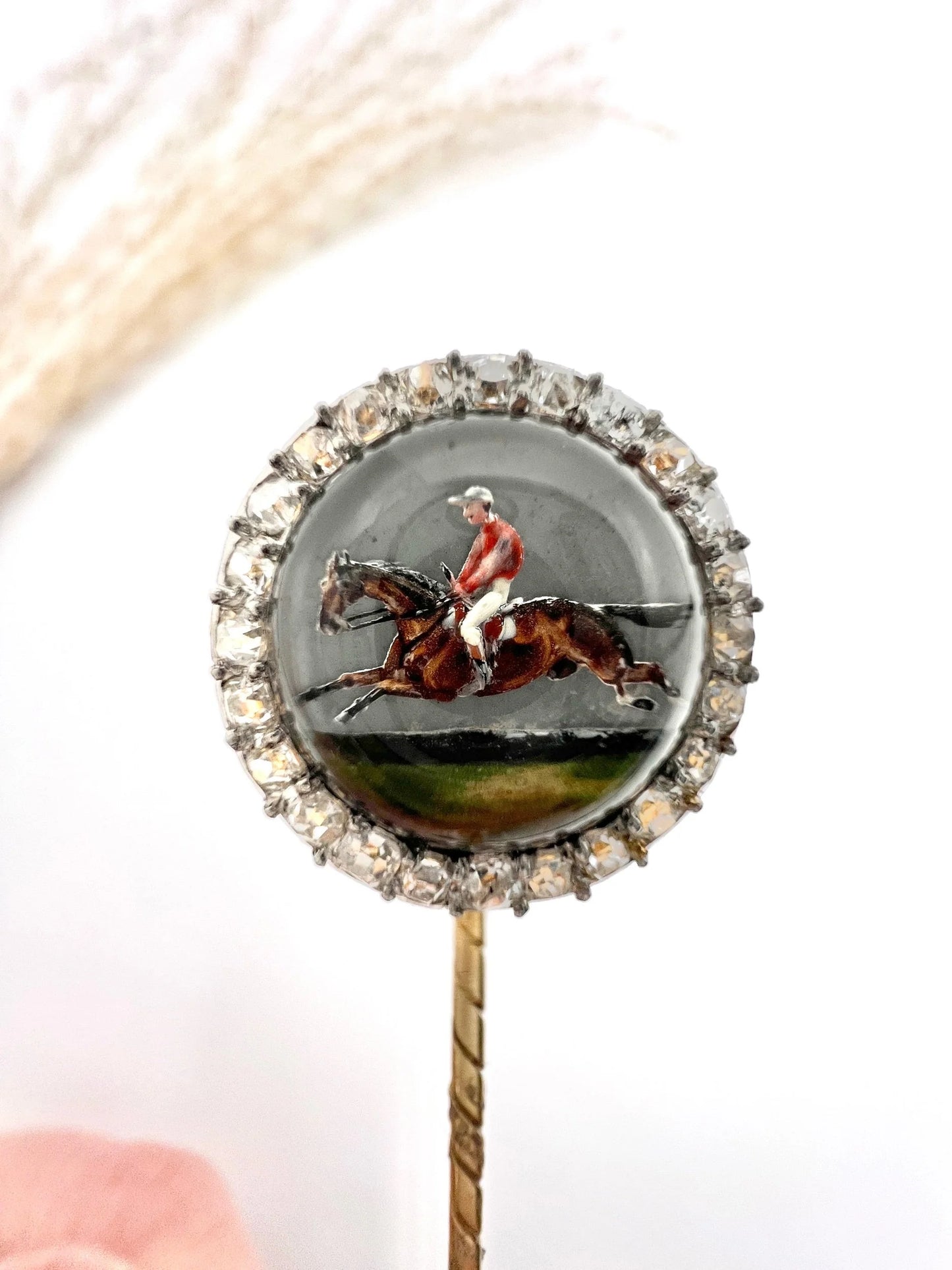 An antique Essex glass and diamond stick pin depicting a jockey riding a horse
