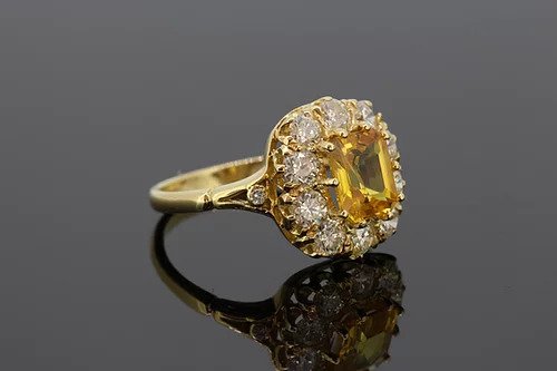 Yellow Sapphire and Diamond Cluster Ring; 2.90ct octagonal cut yellow sapphire surrounded by 1.35cts diamonds, accented with diamond set split shoulders, mounted in 18ct yellow gold.