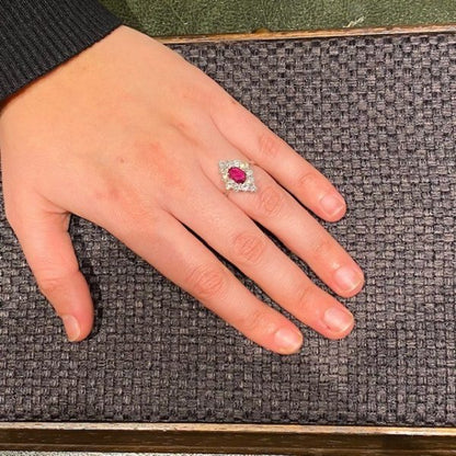 Vintage Ruby and Diamond Cluster Ring; featuring an 0.80ct oval faceted ruby surrounded by 1.80cts round brilliant-cut diamonds, in 18ct white gold. Circa 1970s