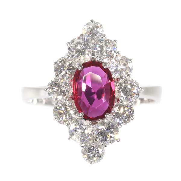 Vintage Ruby and Diamond Cluster Ring; featuring an 0.80ct oval faceted ruby surrounded by 1.80cts round brilliant-cut diamonds, in 18ct white gold. Circa 1970s