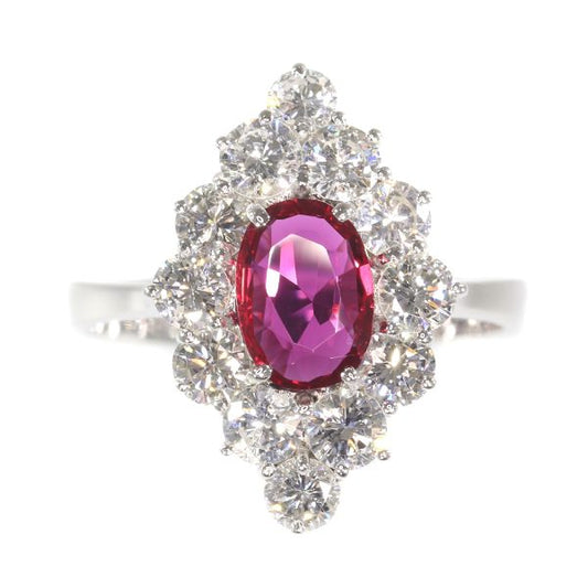 Vintage Ruby and Diamond Cluster Ring; featuring an 0.80ct oval faceted ruby surrounded by 1.80cts round brilliant-cut diamonds, in 18ct white gold. Circa 1970s