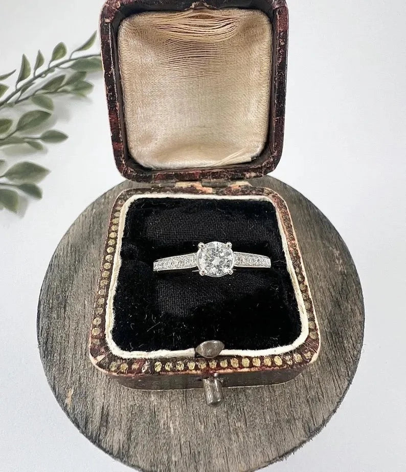 A white gold brilliant cut diamond engagement ring with diamond set shoulders, in a ring box