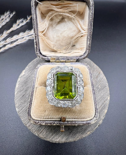 A cushion shaped peridot and diamond cluster ring in white metal, in an antique ring box