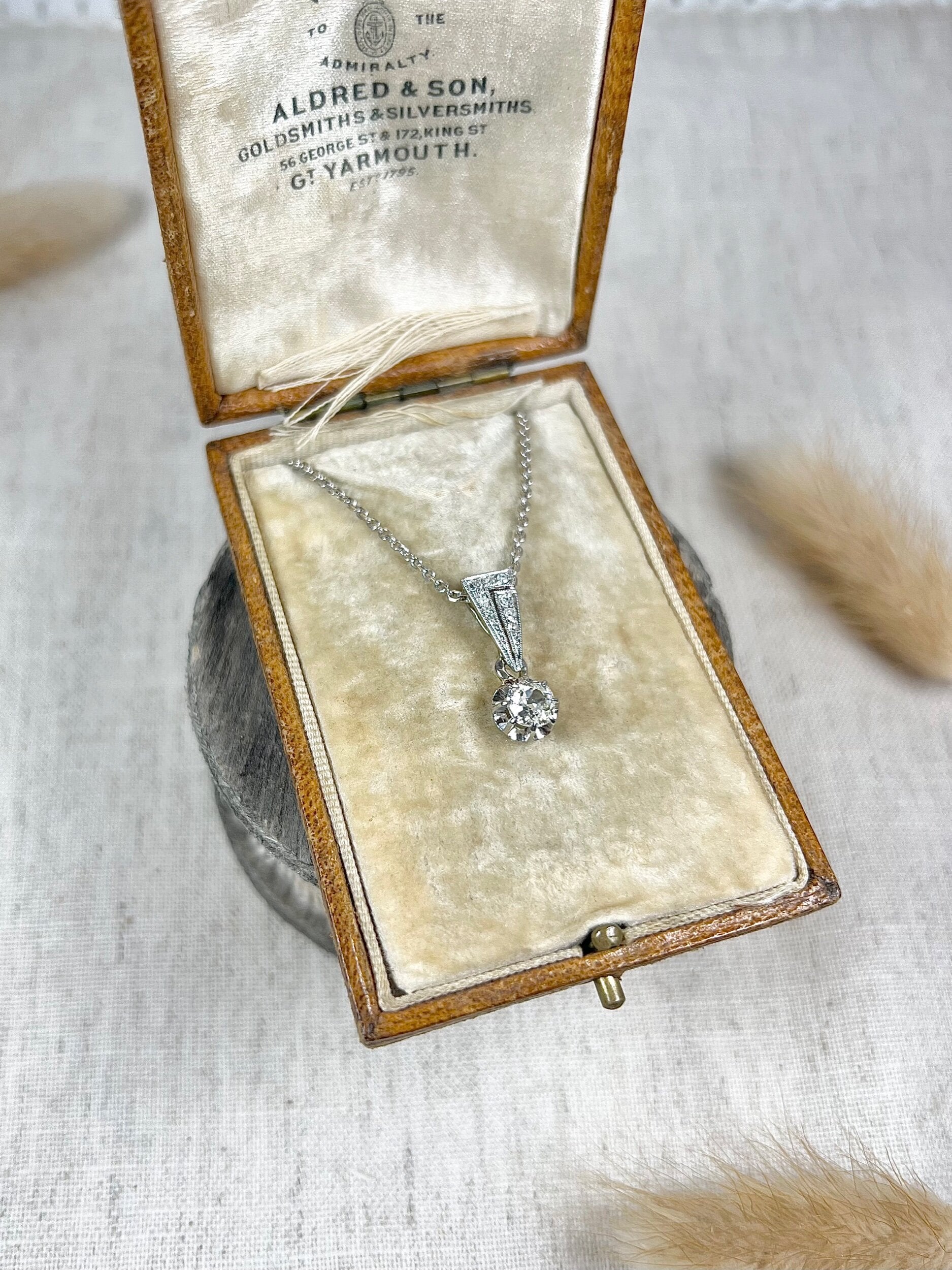 An old cut diamond pendant in white metal with a matching chain, in an antique box