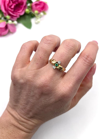 A three stone emerald and diamond ring in yellow and white gold, modelled on a hand