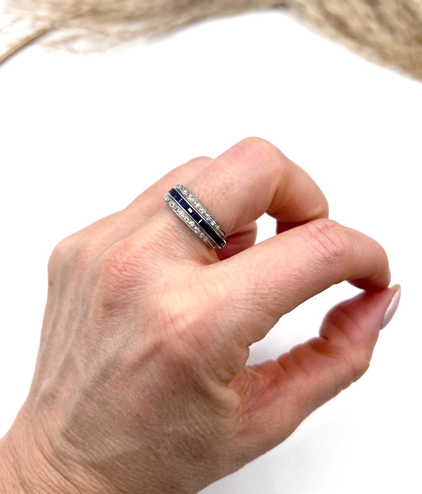 A platinum night and day flip band ring set with diamonds, sapphires and rubies, modelled on a hand
