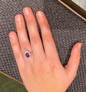 Vintage Ruby and Diamond Cluster Ring; featuring an 0.80ct oval faceted ruby surrounded by 1.80cts round brilliant-cut diamonds, in 18ct white gold. Circa 1970s