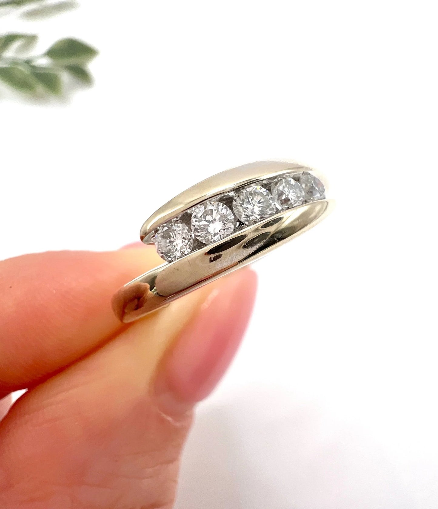 A five stone brilliant cut diamond ring in white gold, held in a hand