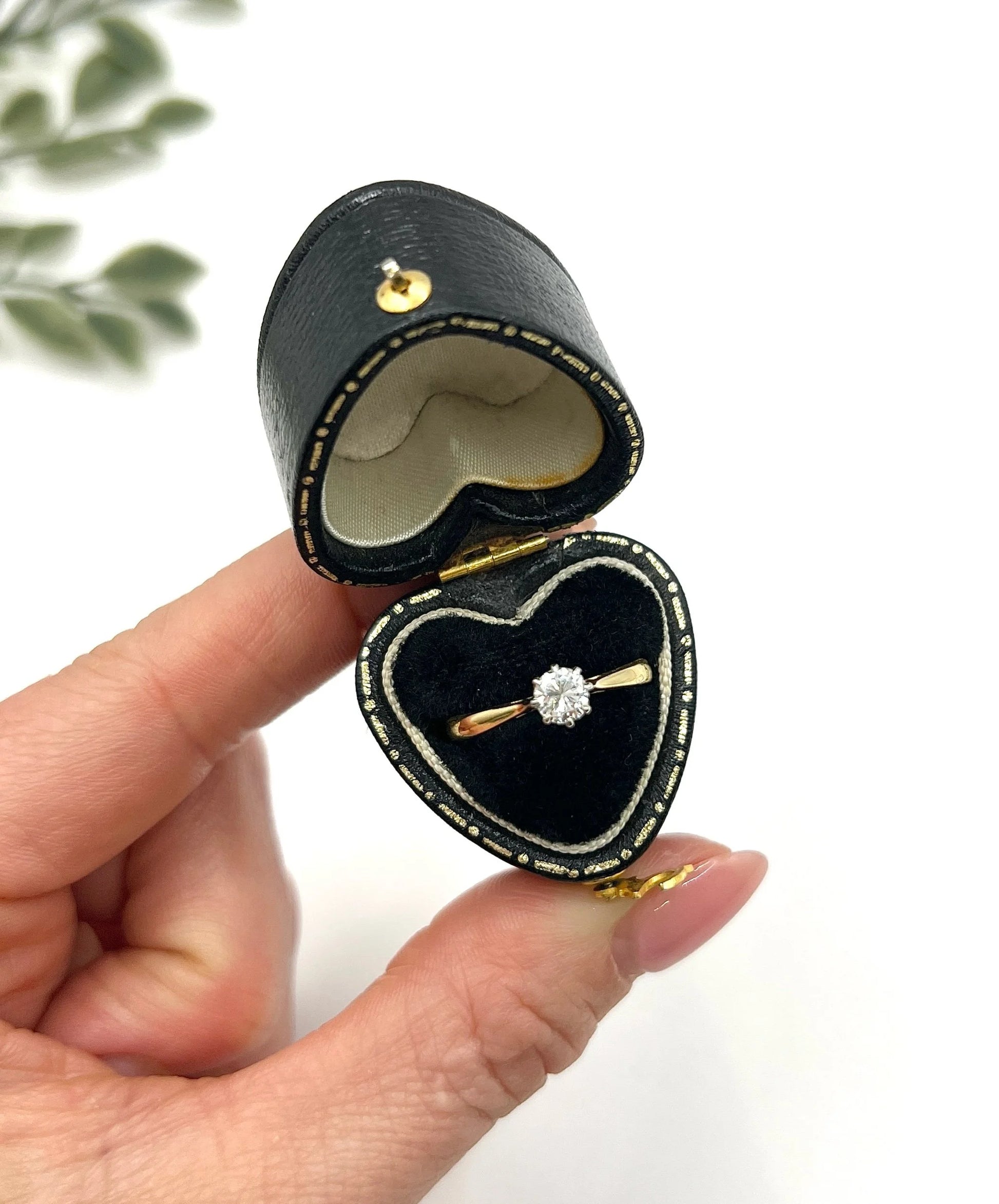 A single stone brilliant cut diamond ring claw set in platinum and yellow gold, in a heart-shaped ring box