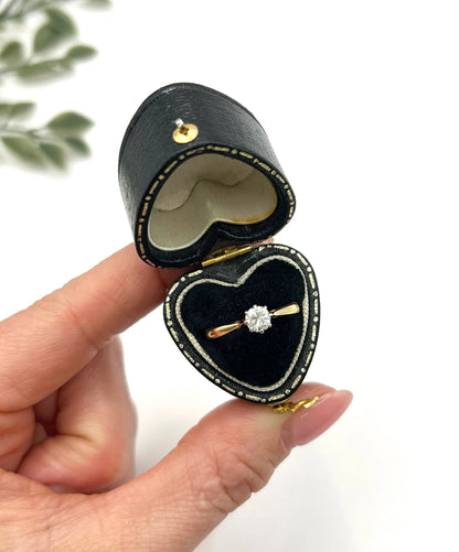 A single stone brilliant cut diamond ring claw set in platinum and yellow gold, in a heart-shaped ring box