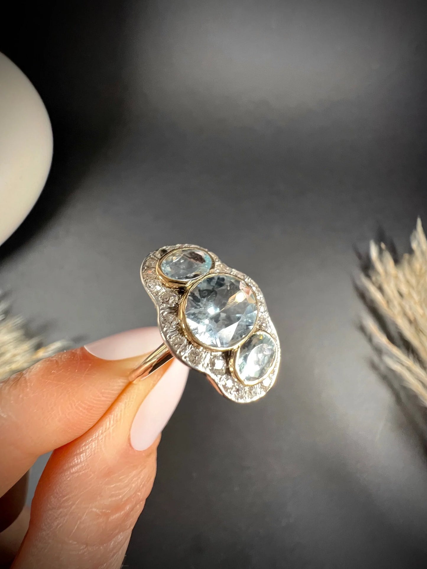 An aquamarine and diamond cocktail cluster ring, held in a hand