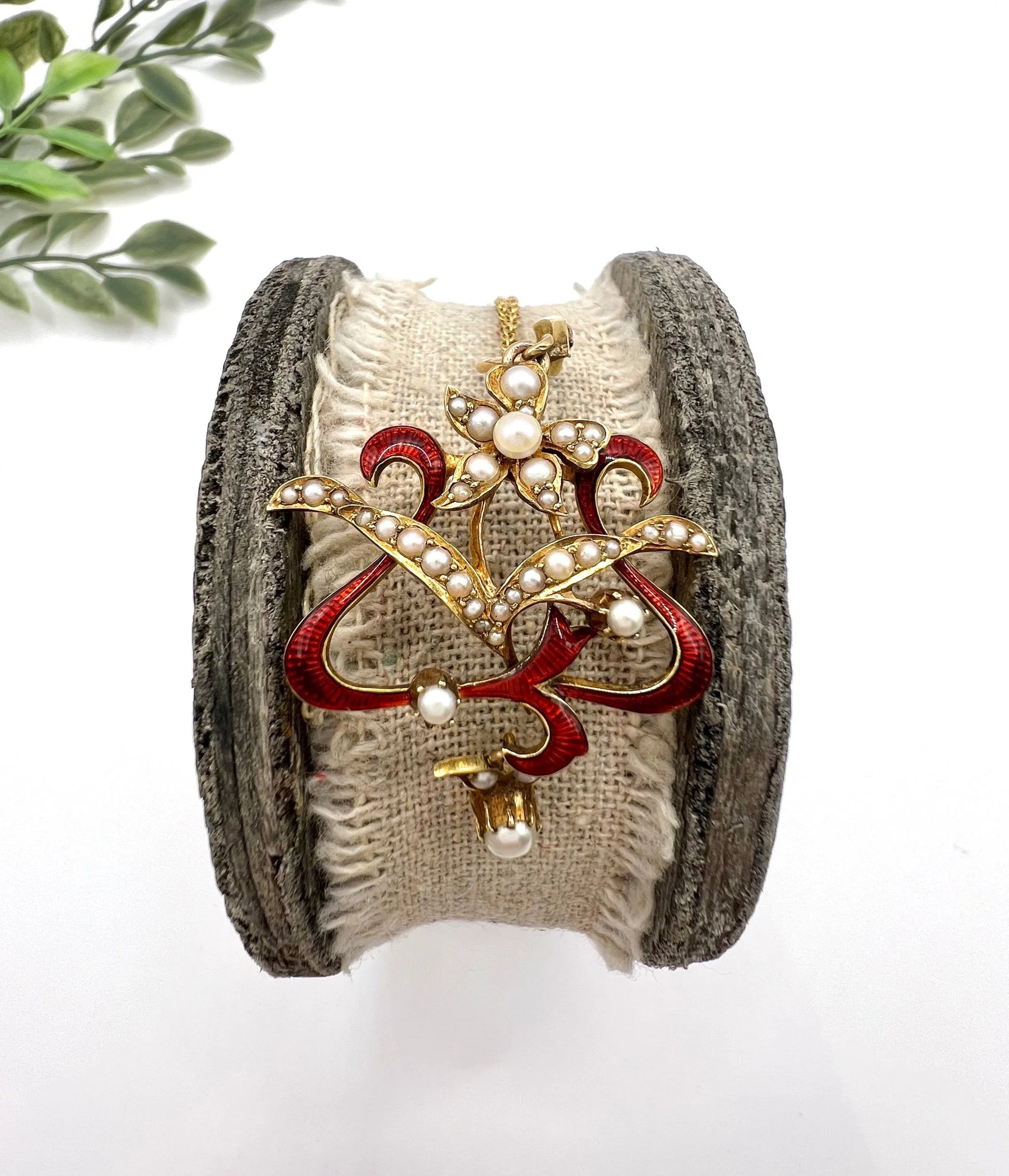 A floral pendant in yellow gold with seed pearls and red enamel