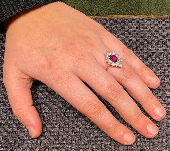 Vintage Ruby and Diamond Cluster Ring; featuring an 0.80ct oval faceted ruby surrounded by 1.80cts round brilliant-cut diamonds, in 18ct white gold. Circa 1970s