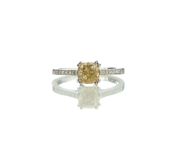 Fancy Yellow Diamond Engagement Ring, 1.24 carat cushion-cut fancy yellow diamond, double four-claw set and accented with diamond set shoulders. Circa 1990s. Fully hallmarked. Comes with AIG certificate.