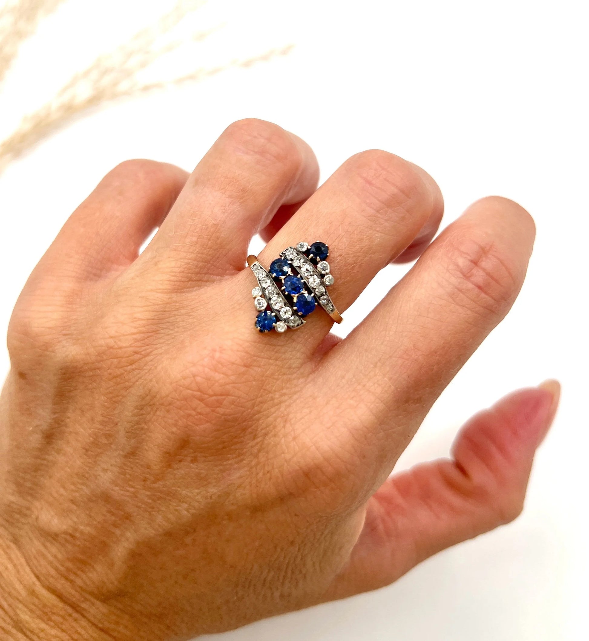 A navette shaped sapphire and diamond ring in yellow gold, modelled on a hand