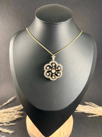 A floral design diamond set pendant/brooch on a gold chain modelled on a black jewellery bust